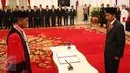 Hakim MK, Saldi Isra disaksikan Presiden Joko Widodo sebelum menandatangani dokumen pelantikan sebagai Hakim MK di Istana Negara, Jakarta, Selasa (11/4). Saldi Isra menggantikan Patrialis Akbar. (Liputan6.com/Angga Yuniar)