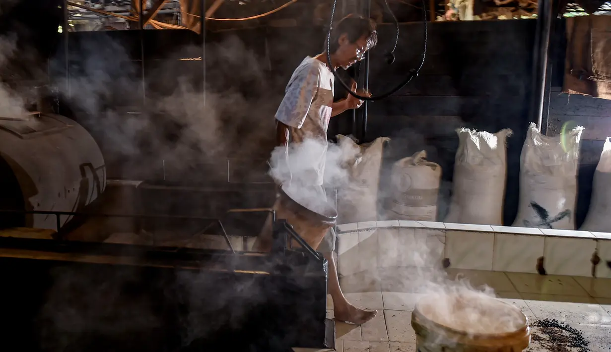 Seorang pekerja membawa biji kopi robusta setelah disangrai secara tradisional di sebuah produsen biji kopi kecil di Banda Aceh (14/11/2020). (AFP/Chaideer Mahyuddin)