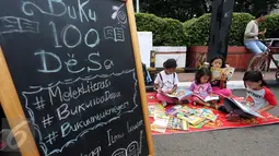 Sejumlah anak membaca buku di Kawasan Bundaran HI saat berlangsungnya Hari Bebas Kendaraan Bermotor, Jakarta, Minggu (2/4). Kegiatan ini dilakukan sebagai ajakan kampanye "Budayakan Membaca dari Desa untuk Indonesia". (Liputan6.com/Johan Tallo)