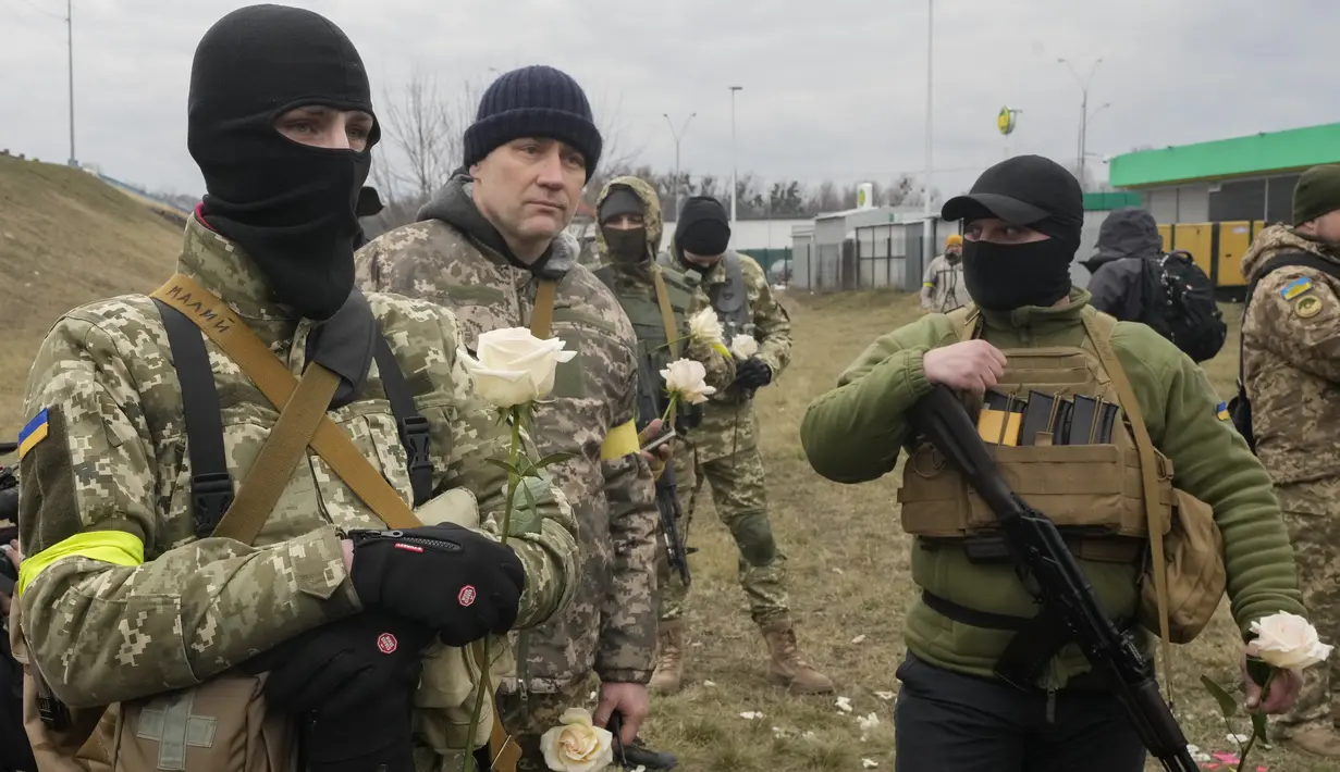 Anggota Pasukan Pertahanan Teritorial Ukraina memegang bunga selama upacara pernikahan untuk Lesia Ivashchenko dan Valerii Fylymonov di pos pemeriksaan di Kiev, 6 Maret 2022. Kedunya menikah dengan upacara seadanya yang dilakukan korps mereka di tengah invasi Rusia. (AP/Efrem Lukatsky)