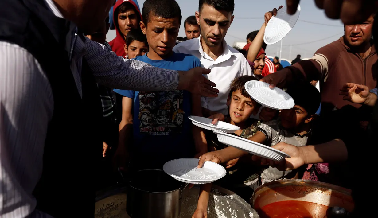 Sejumlah anak saat mengambil makanan saat mengungsi di kamp Khazer, Irak, (11/11). Warga terpaksa melarikan diri saat Pasukan Irak dan kelompok militan ISIS bentrok memberebutkan kota Mosul. (REUTERS/Zohra Bensemra)