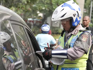 Petugas menilang pengendara mobil yang melanggar aturan pembatasan kendaraan sistem ganjil genap di kawasan Sudirman, Jakarta, Selasa (30/8). Hari ini resmi diberlakukan denda bagi pelanggar aturan sistem ganjil genap. (Liputan6.com/Yoppy Renato)