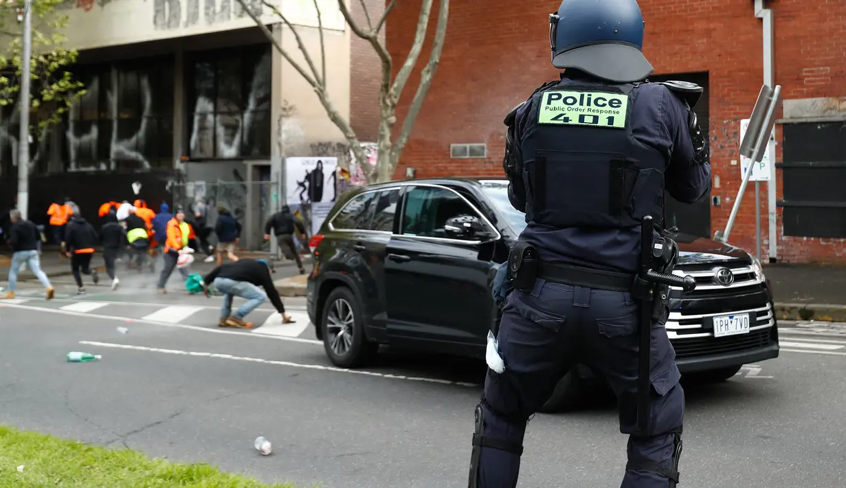 Seorang polisi turun tangan setelah demonstran menabrak mobil polisi selama protes terhadap peraturan Covid-19 di Melbourne (21/9/2021). Ribuan orang membuat kekacauan dan bentrok dengan polisi di kota dan mengambil alih jalan raya utama Melbourne saat protes terjadi. (AFP/STR)