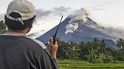 Seorang relawan menggunakan walkie talkie-nya saat memantau Gunung Merapi saat erupsi di Sleman (27/1/2021). Sekitar 150 warga di lereng barat daya Gunung Merapi di Kabupaten Sleman, DIY, mengungsi dari rumah, Rabu (27/1/2021) sore. (AP Photo/Slamet Riyadi)