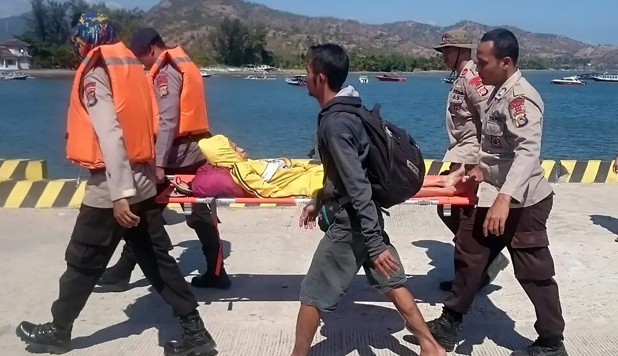 Polisi menandu seorang korban terluka saat ratusan orang berusaha meninggalkan Gili Trawangan, NTB, Senin (6/8). Hingga pukul 10.30 WIB, petugas telah mengevakuasi 70 orang, terdiri dari 64 WNI dan 6 WNA. (Handout/Indonesia Water Police/AFP)