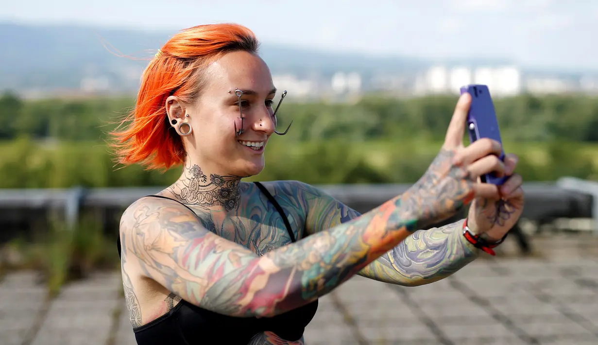  Kaitlin berfoto selfie dengan dua mata kail yang menembus kulit sebelum melakukan aksi berani menggantungkan tubuhnya di Zagreb, Kroasia, (7/6). Kaitlin terlihat tenang meski sejumlah mata kail tajam menembus kulitnya. (REUTERS/Antonio Bronic)