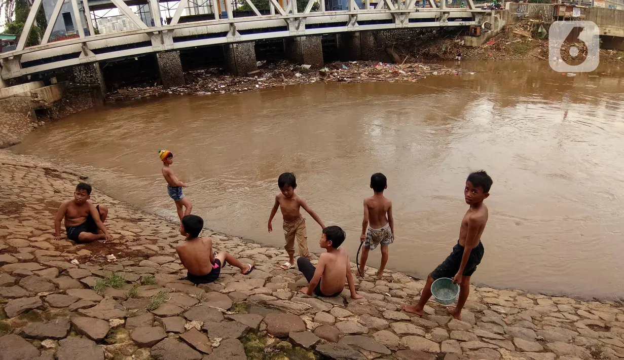 Sejumlah anak bermain di Bantaran sungai Kanal Banjir Barat, Tanah Abang, Jakarta, Sabtu (4/1/2020). Minimnya lahan bermain terpaksa membuat anak-anak harus bermain di bantaran Banjir Kanal Barat meskipun dapat membahayakan keselamatan dirinya. (Liputan6.com/Angga Yuniar)