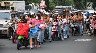 Ratusan pelajar SMA mendorong sepeda motor mereka di Bundaran Simpang Lima, Semarang, Jawa Tengah, Kamis (3/5). Aparat Polrestabes Semarang mengamankan mereka karena mengendarai motor tanpa helm. (Liputan6.com/Gholib)