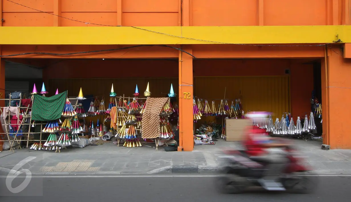 Pengendara motor melintas di depan pedagang terompet di kawasan Kota Tua, Jakarta. Selasa (27/12). Terompet tersebut dijual dengan harga bervariasi, mulai dari Rp3ribu hingga Rp15ribu, tergantung bentuk dan ukurannya. (Liputan6.com/Immanuel Antonius)