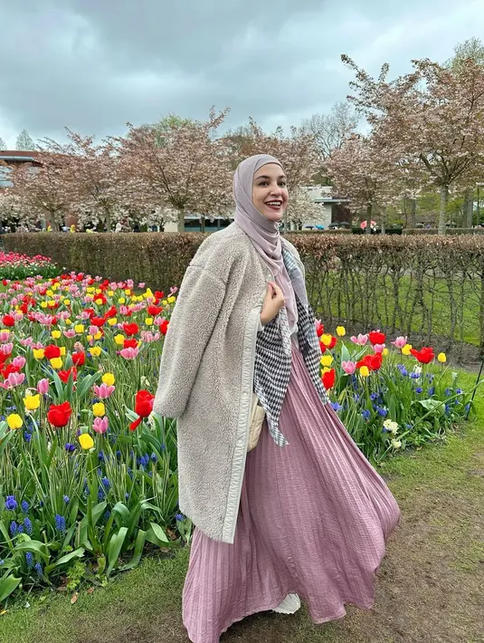 Liburan di Belanda, Shireen Sungkar tampil menawan pakai coat dan rok pleats nuansa pink sambil pose di depan bunga tulip. [Foto: IG/shireensungkar].