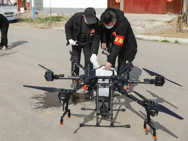 Warga memasukan cairan disinfektan yang akan dibawa drone sebelum melakukan penyemprotan di sebuah desa di Pingdingshan, di Provinsi Henan, China (31/1/2020). Warga Henan di China memanfaatkan teknologi drone untuk menyemprotkan cairan disinfektan dari udara.  (AFP Photo/Str)