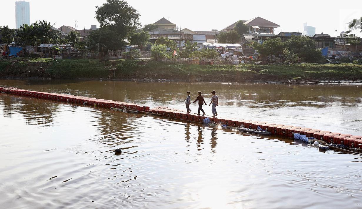 Anak-anak melintasi jembatan yang ada di Kanal Banjir Barat, Jakarta, Jumat (23/3). Selain mahalnya sewa kolam renang, berenang Kanal Banjir Barat dipilih anak-anak tersebut karena minimnya lahan bermain. (Liputan6.com/Immanuel Antonius)