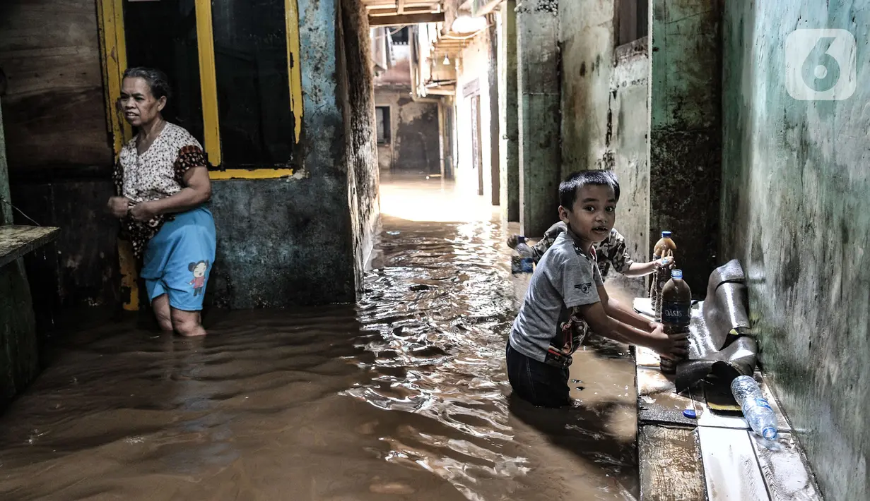 Anak-anak bermain air saat banjir merendam permukiman Kebon Pala, Jatinegara, Jakarta, Minggu (25/10/2020). Tidak adanya tanggul antara permukiman dan Kali Ciliwung menyebabkan banjir yang meluap sejak dini hari tadi lambat surut. (merdeka.com/Iqbal Nugroho)