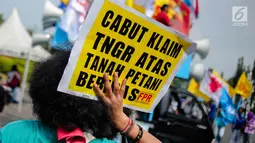 Seorang pengunjuk rasa menunjukkan poster saat menggelar aksi di depan Istana Negara, Jakarta, Senin (25/9). Aksi tersebut sebagai peringatan Hari Tani Nasional (HTN) 2017. (Liputan6.com/Faizal Fanani)