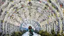 Seorang wanita melintasi terowongan yang dihias dengan lampu-lampu meriah untuk menyamb ut Natal dan Tahun Baru di Moskow, Rusia, Senin (17/12). (Kirill KUDRYAVTSEV/AFP)