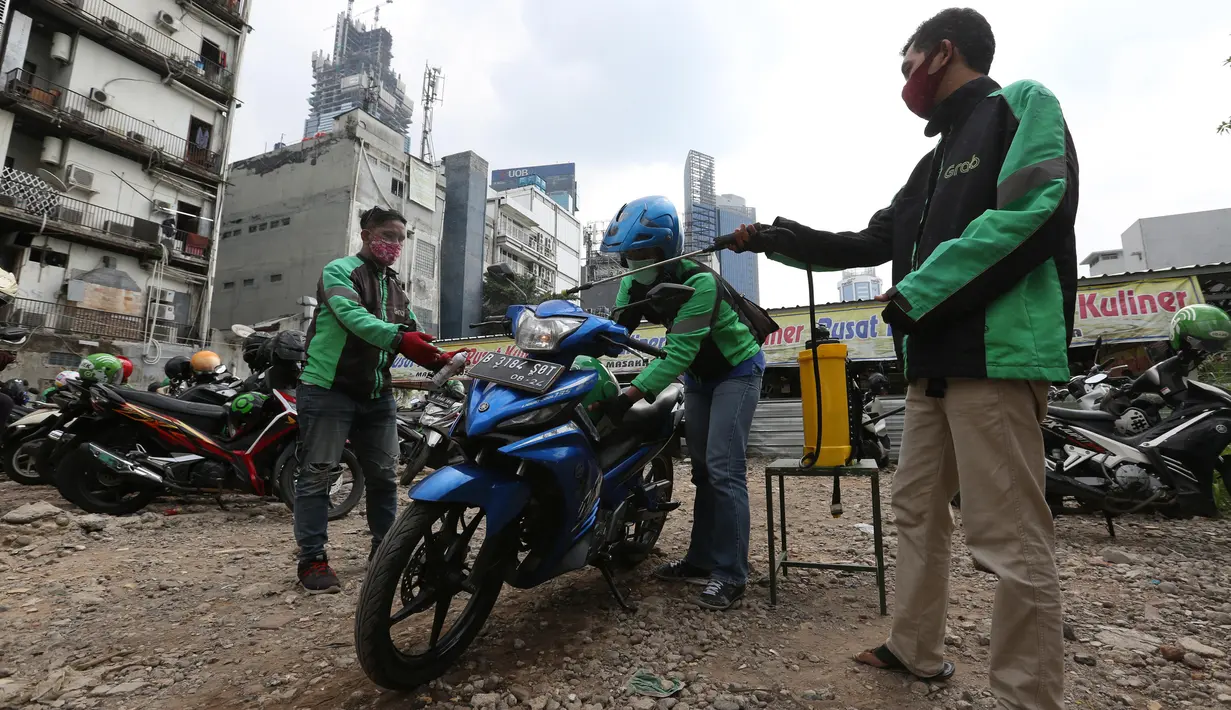 Pengemudi ojek online melakukan penyemprotan disinfektan sebelum mengangkut penumpang di Shelter Sudirman, Jakarta, Senin (8/6/2020). Pemprov DKI mulai mengizinkan ojek daring maupun konvensional mengangkut penumpang di PSBB transisi dengan menerapkan protokol kesehatan. (Liputan6.com/Angga Yuniar)