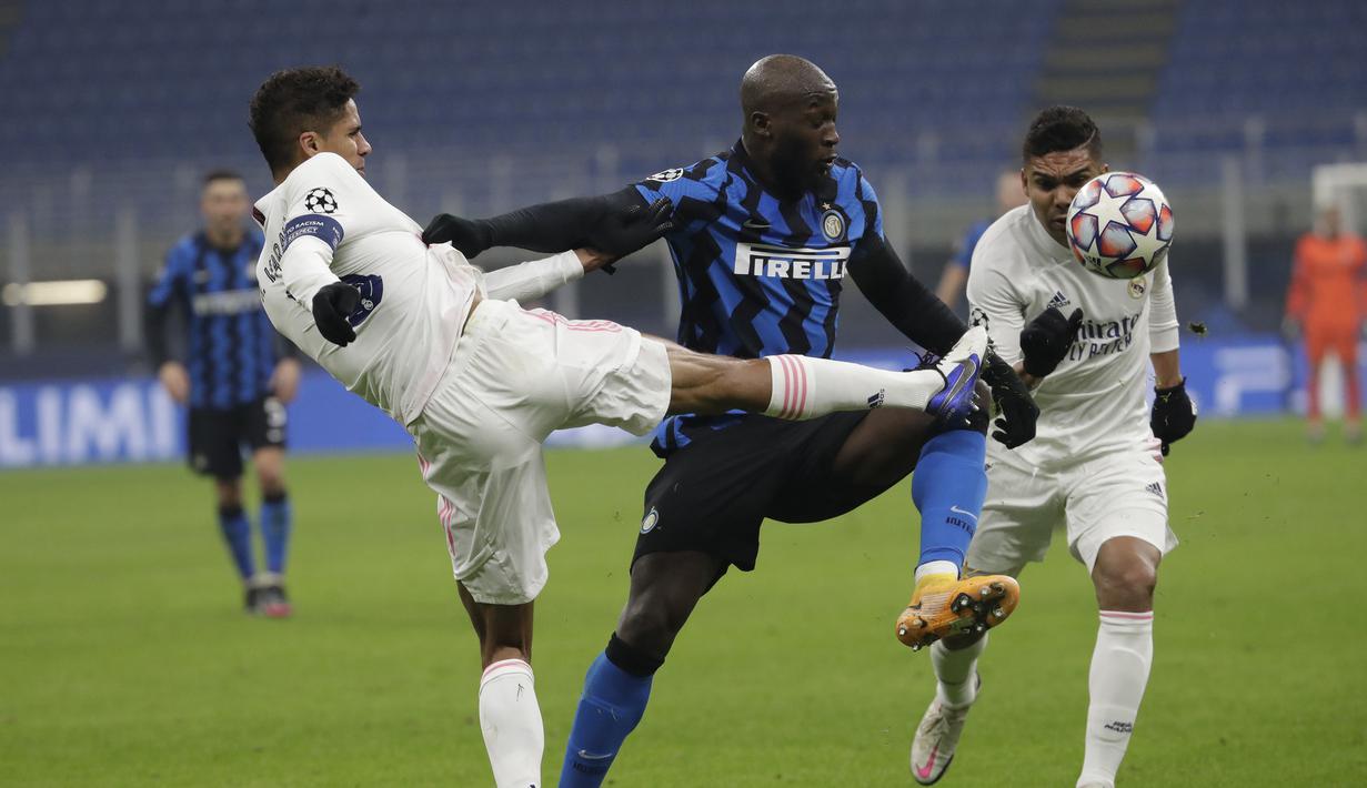 Bek Real Madrid, Raphael Varane, berebut bola dengan penyerang Inter Milan, Romelu Lukaku, pada laga lanjutan Liga Champions di Giuseppe Meazza, Kamis (26/11/2020) dini hari WIB. Real Madrid menang 2-0 atas Inter Milan. (AP Photo/Luca Bruno)