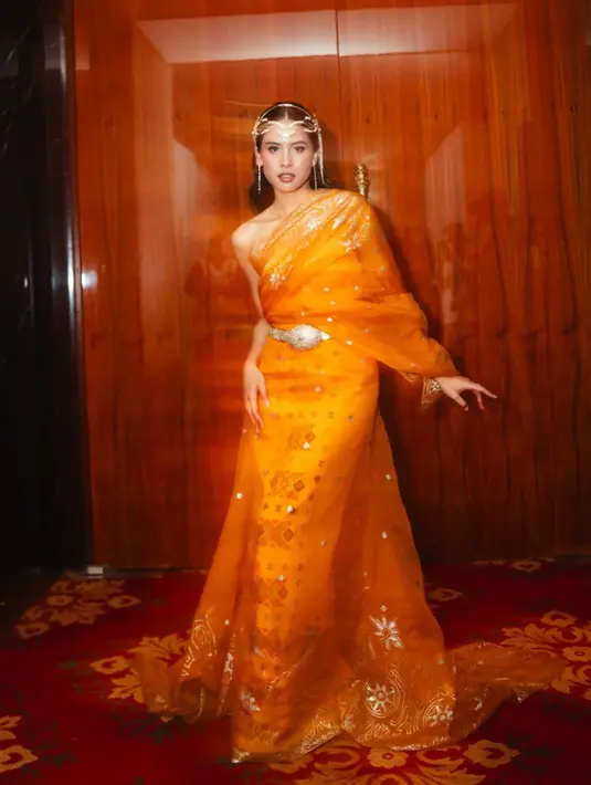 Maudy Ayunda terlihat menawan kenakan busana yang mirip dengan sari. Ia memadukan off shoulder dress berwarna kuning dengan kain transparan bermotif batik prada yang elegan bergaya one shoulder [@maudyayunda]