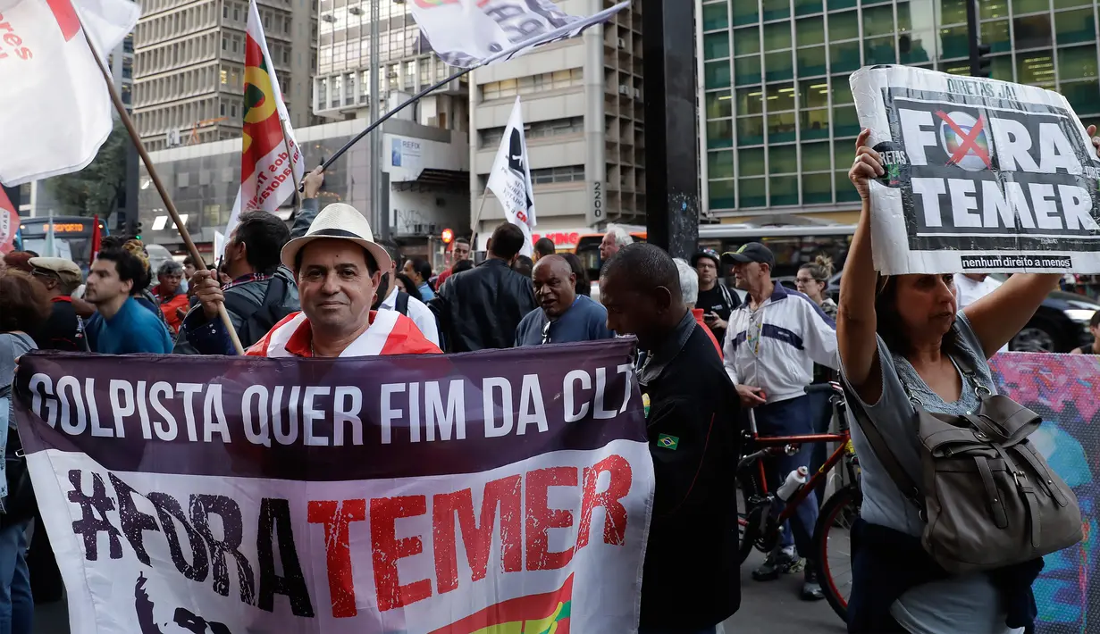 Seorang demonstran memperlihatkan spanduk bertuliskan “Keluarkan Temer!” dalam unjuk rasa di Sao Paulo, Brasil, Rabu (2/8). Aksi ini berlangsung di beberapa negara bagian Brasil dan sekitar ratusan orang terlibat dalam protes tersebut (AP/Andre Penner)