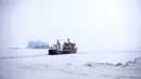 Kapal pemecah es membuat jalur untuk kapal kargo dengan latar belakang gunung es dekat pelabuhan di Pulau Alexandra Land dekat Nagurskoye, Rusia, Senin (17/5/2021). Pulau Alexandra Land merupakan pangkalan militer paling utara Rusia. (AP Photo/Alexander Zemlianichenko)