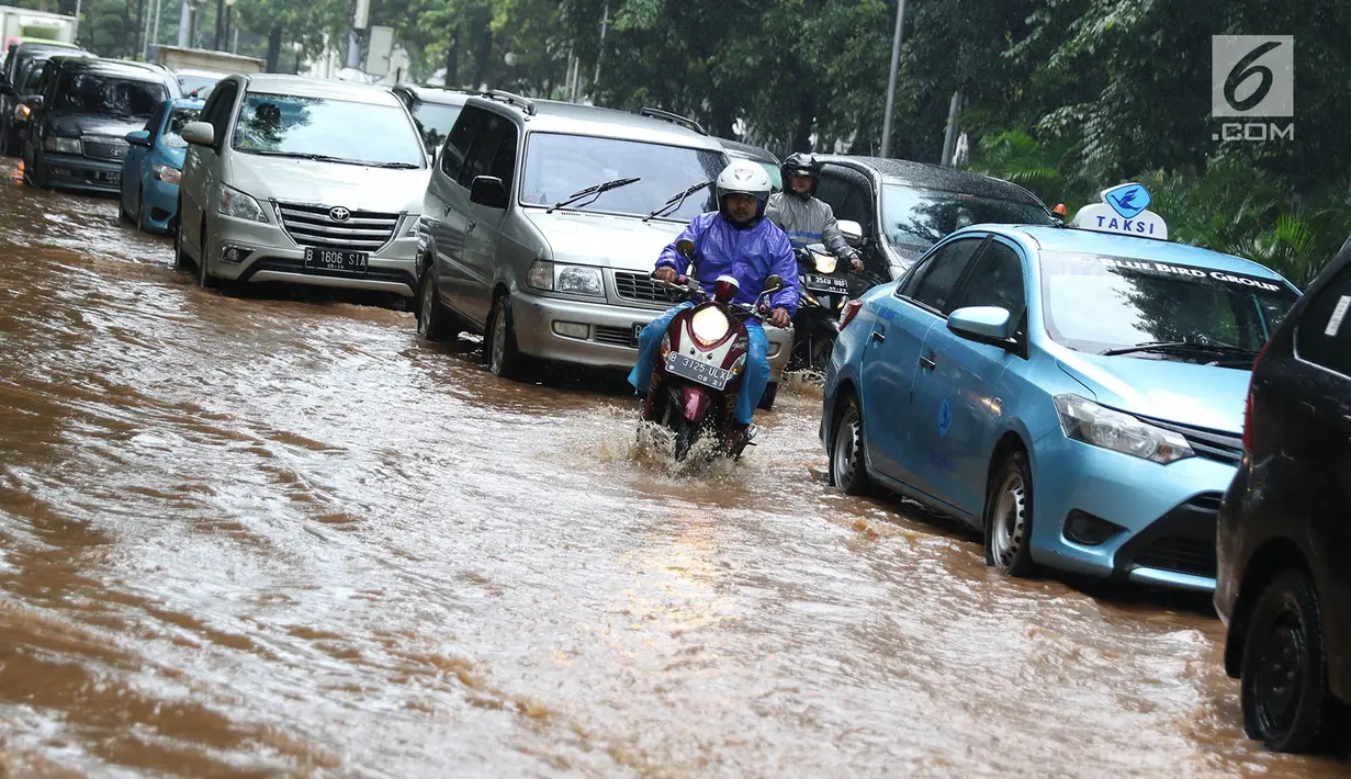Pengendara motor melintas di antara mobil yang terjebak kemacetan saat banjir di Jalan Lapangan Banteng Utara, Jakarta, Kamis (15/2). Hujan deras yang mengguyur dan buruknya drainase menyebabkan kawasan tersebut banjir (Liputan6.com/Immanuel Antonius)