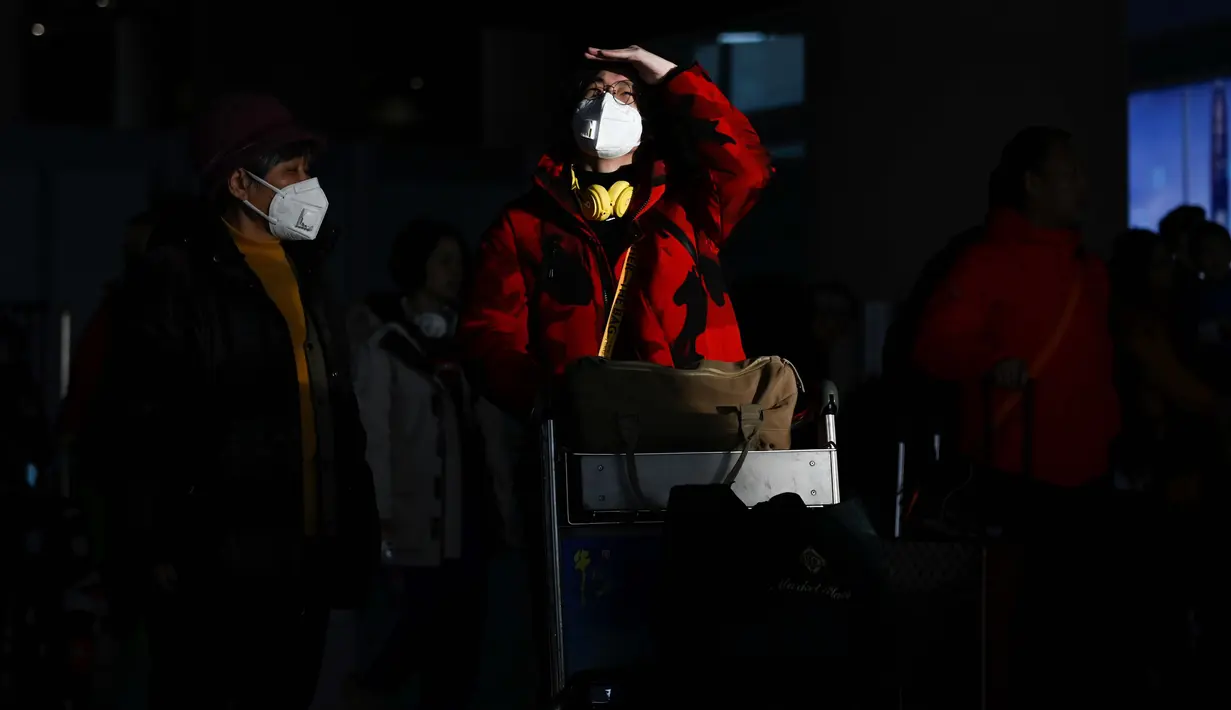 Dua penumpang yang mengenakan masker tiba di Bandara Internasional Beijing pada 20 Januari 2020,menjelang Tahun Baru Imlek. China berada di tengah-tengah kesibukan migrasi manusia tahunan ketika jutaan orang pulang ke kampung halaman mereka untuk menikmati libur Tahun Baru Imlek. (WANG Zhao/AFP)