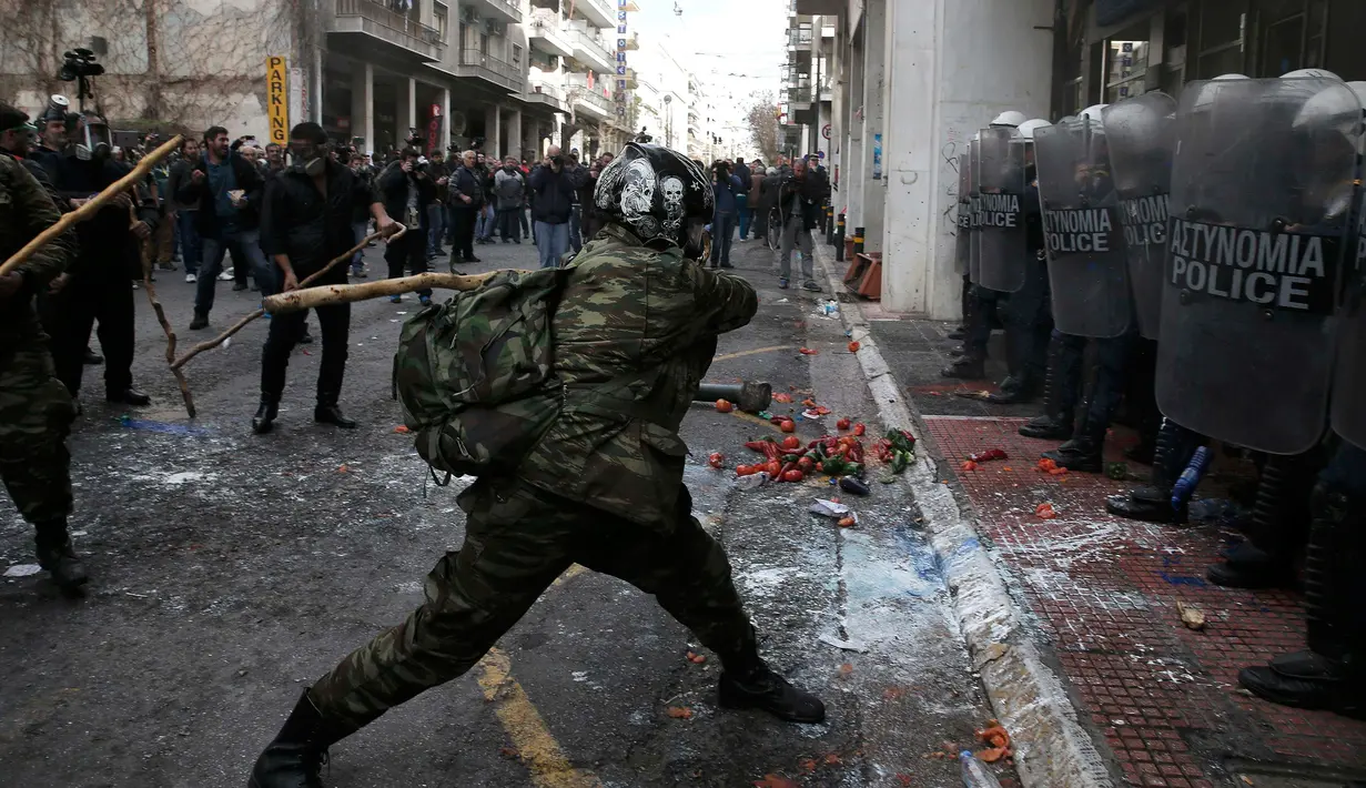 Seorang petani Yunani dari wilayah Crete saat bentrok dengan polisi selama protes petani terhadap perubahan peraturan pensiun yang direncanakan di luar Kementerian Pertanian, Athena, Yunani, Jumat (12/2). (REUTERS/Alkis Konstantinidis)	