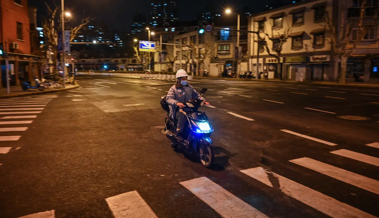 Seorang pria mengendarai skuter di jalan sebelum dimulainya lockdown tahap kedua sebagai tindakan pencegahan terhadap virus corona COVID-19 di Shanghai, China, 31 Maret 2022. (Hector RETAMAL/AFP)