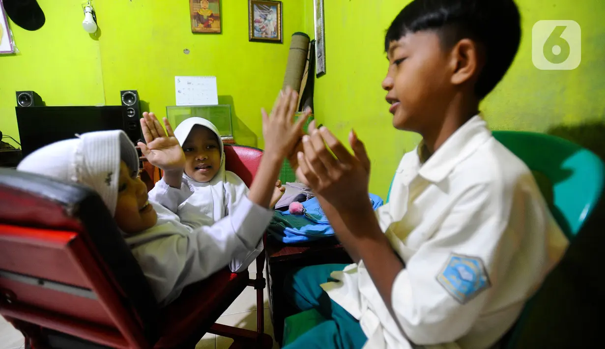 Kembar siam Al Dewi Putri Ningsih (9) dan Al Putri Anugrah (9) saat bermain dengan sang kakak di rumah mereka kawasan Sucinaraja, Garut, Jawa Barat, Senin (22/5/2023). (merdeka.com/Arie Basuki)