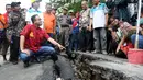 Gubernur DKI Anies Baswesdan berjongkok memeriksa retakan jalan di Kelurahan Kebon Manggis, Kecamatan Matraman, Jakarta Timur, Jumat (16/2). Kehadiran Anies yang mengenakan baju tradisional China itu mengundang perhatian warga. (Liputan6.com/Johan Tallo)