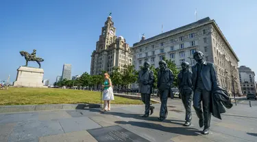 Patung The Beatles dan Royal Liver Building di tepi pantai Liverpool, Rabu (21/7/2021). Kota Liverpool Inggris telah dihapus dari daftar situs warisan dunia UNESCO karena hadirnya bangunan baru, termasuk stadion baru klub bola Everton, yang merusak daya tarik dermaga Victoria. (Peter Byrne/PA via AP