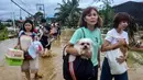 Warga membawa barang-barang dan hewan peliharaan mereka saat melintasi jalan yang tergenang air saat dievakuasi dari rumah-rumah mereka yang terendam banjir di Kota Liloan, Provinsi Cebu, Filipina, pada Rabu 5 November 2025. Palang Merah Filipina menerima banyak panggilan darurat dari warga yang membutuhkan evakuasi segera. (Alan TANGCAWAN/AFP)