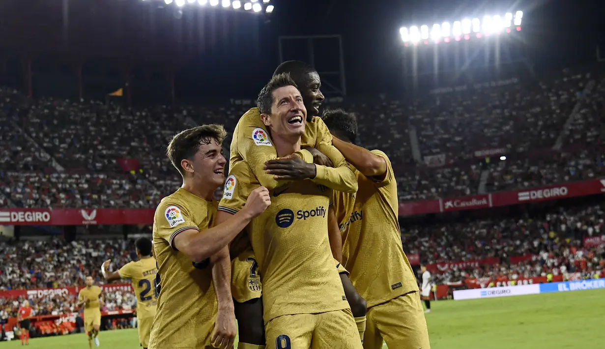 Penyerang Barcelona, Robert Lewandowski (tengah) berselebrasi dengan rekan satu timnya setelah mencetak gol ke gawang Sevilla pada pertandingan lanjutan La Liga Spanyol di Seville, Spanyol, Sabtu (3/9/2022). Barcelona menang telak atas Sevilla 3-0. (AP Photo/Jose Breton)