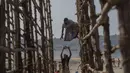 Seorang nelayan wanita mengeluarkan ikan dari struktur yang terbuat dari tiang bambu setelah dijemur di sebuah koloni nelayan di Mumbai, India, Rabu (29/12/2021). (AP Photo/Rafiq Maqbool)
