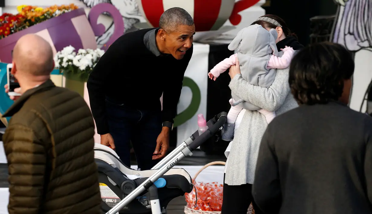 Presiden AS, Barack Obama menyapa seorang balita yang digendong ibunya saat merayakan Halloween di Gedung Putih, Washington, Senin (31/10). Sebanyak 4.000 orang diperkirakan mengunjungi White House untuk merayakan Hallowen. (REUTERS / Jonathan Ernst)