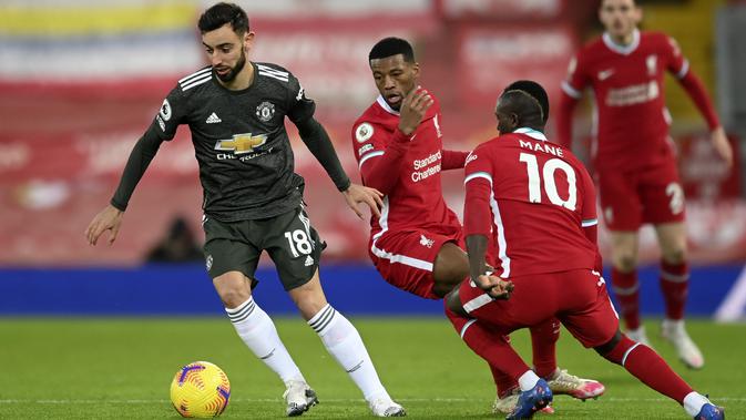Gelandang Manchester United, Bruno Fernandes membawa bola dari kejaran dua pemain Liverpol, Sadio Mane dan Georginio Wijnaldum pada pertandingan lanjutan Liga Inggris di Stadion Anfield, Senin (18/1/2021). (Liverpool bermain imbang atas MU 0-0. (Michael Regan/Pool via AP)