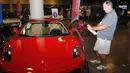 Pengunjung mengambil gambar mobil Ferrari F430 yang dipamerkan oleh Auctions America di Florida, 31 Maret 2017. Mobil berwarna merah menyala produksi 2007 itu pernah digunakan oleh Presiden AS, Donald Trump, selama empat tahun. (LEILA MACOR/AFP)