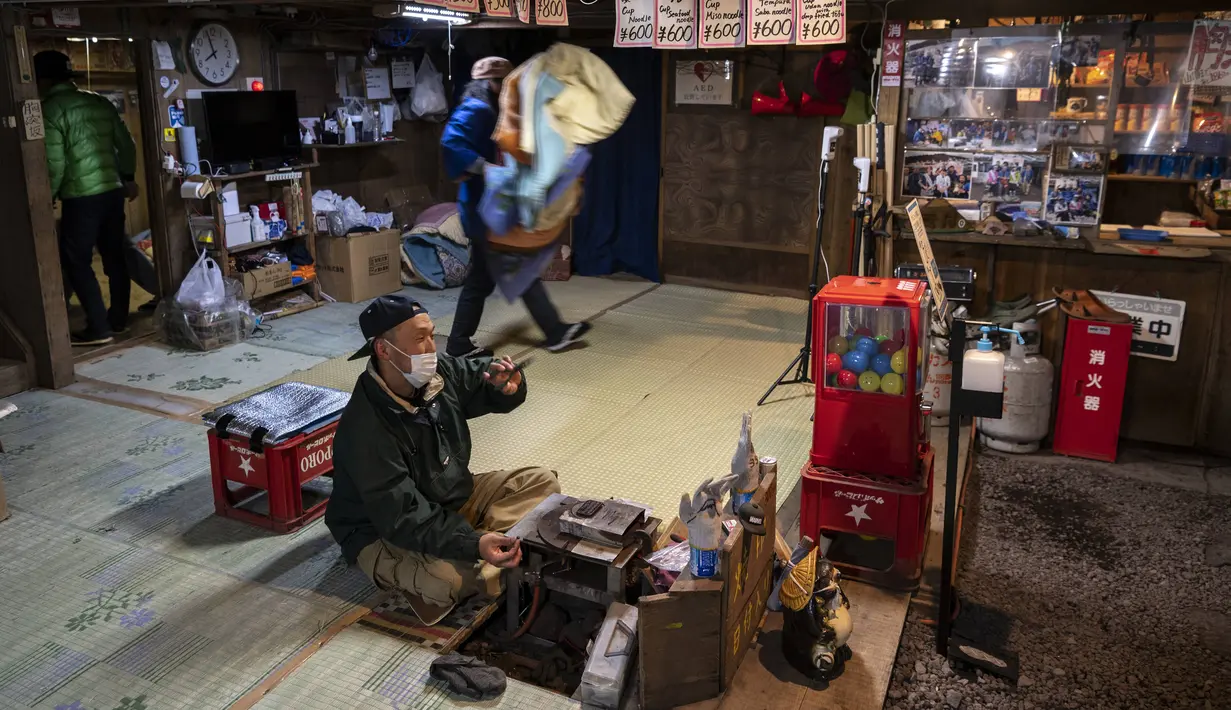 Foto pada 18 Juli 2021 menunjukkan orang-orang bekerja di dalam gubuk yang menjual makanan dan barang-barang lainnya, di dekat puncak Gunung Fuji, barat Tokyo. Pemandangan matahari terbit di atas lautan awan adalah hadiah indah bagi yang mencapai puncak tertinggi di Jepang. (Charly TRIBALLEAU/AFP)