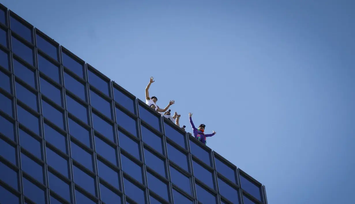 Pendaki Alain Robert (kanan) atau Spiderman Prancis bersama Marcin Banot, Alexis Landot, dan Leo Urban melakukan perayaan di puncak Menara Total usai memanjatnya di La Defense, Paris, Prancis, 7 September 2021. (THOMAS SAMSON/AFP)