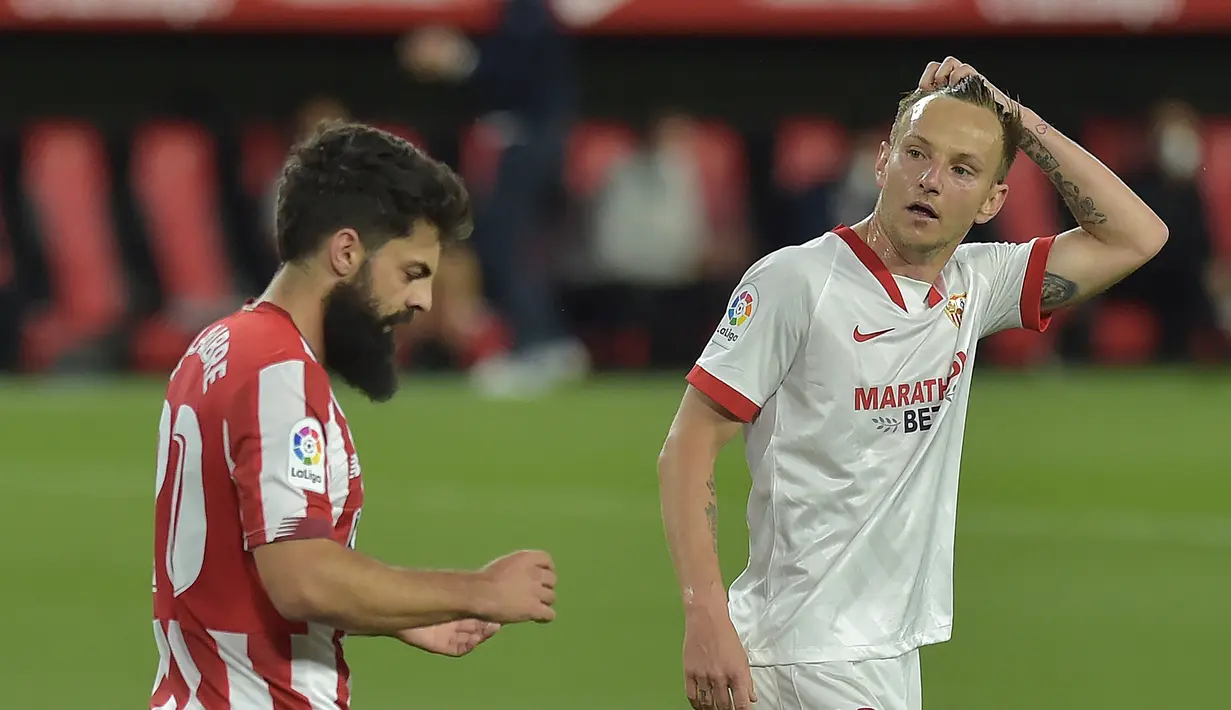 Gelandang Sevilla, Ivan Rakitic (kanan) bereaksi di samping penyerang Athletic Bilbao, Asier Villalibre pada pertandingan La Liga Spanyol di stadion Ramon Sanchez Pizjuan, Seville, Selasa (4/5/2021). Kekalahan atas Bilbao, membuat Sevilla gagal mendekati tiga tim teratas Liga Spanyol. (AFP/Cristina