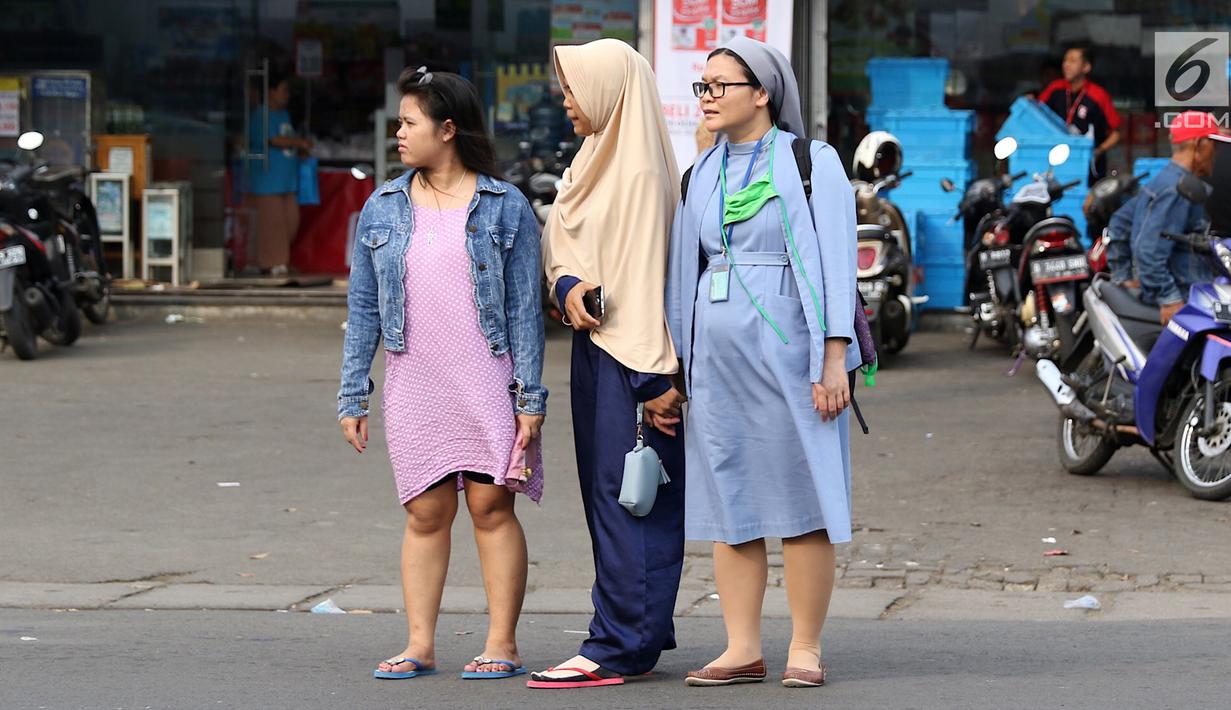 Momen ketika biarawati bergandeng tangan dengan wanita berkerudung saat menyeberangi jalan di kawasan Lenteng Agung, Jakarta, Rabu (18/4). Keharmonisan keduanya dapat menjadi contoh bagi masyarakat dalam menjaga kedamaian. (Liputan6.com/Immanuel Antonius)
