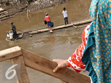 Warga menaiki eretan untuk menyeberangi Kali Ciliwung, Jakarta, Senin (30/11). Tidak adanya fasilitas jembatan menyebabkan warga memilih eretan sebagai sarana penyeberangan sehari-hari, meskipun dengan kondisi seadanya. (Liputan6.com/Immnuel Antonius)