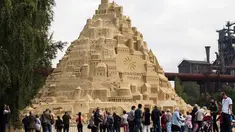 Seniman saat menyelesaikan istana pasir di Landschaftspark di Duisburg, Jerman , (1/9). Seniman dari Duisburg burusaha meraih Guinness Book of World Records dengan membuat istana pasir tertinggi yang pernah ada. (Marcel Kusch / dpa via AP)