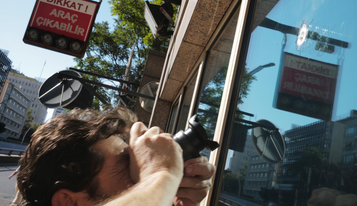 Fotografer memfoto kaca bilik keamanan Kedutaan Besar Amerika Serikat tertembak di Ankara, Turki, (20/8). Serangan ini terjadi saat hubungan antara AS dan Turki sedang memanas terkait penahanan pastor Amerika, Andrew Brunson. (AP Photo/Burhan Ozbilici)