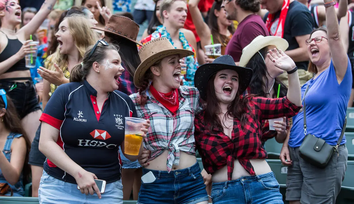 Sejumlah wanita bersorak saat menyaksikan hari pertama turnamen rugby sevens Hong Kong, China (6/4). Turnamen ini berlangsung selama tiga hari dan diselenggarakan setiap tahun oleh Hong Kong Rugby Union (HKRU). (AFP Photo/Isaac Lawrence)
