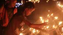 Anak-anak menyalakan lampu minyak saat perayaan tumbilotohe atau penyalaan berjuta lampu minyak di akhir Ramadan di Kota Gorontalo, Jumat (31/5/2019). Lampu minyak tersebut dipasang menghiasi jalan, halaman rumah, masjid bahkan sungai. (Liputan6.com/Arfandi Ibrahim)