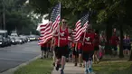 Sejumlah warga yang tergabung dalam kelompok veteran berlari sambil membawa bendera Amerika Serikat untuk menunjukan solidaritas terkait penembakan di Virginia, AS (14/6). (Alex Wong/Getty Images/AFP)