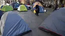 Pejalan kaki melewati deretan tenda yang didirikan para tunawisma di kawasan Martin Place, pusat kota Sydney, 2 Agustus 2017. Di perkampungan tenda para tunawisma itu mereka bertahan hidup dengan membuka lapak di pinggir jalan. (PETER PARKS / AFP)