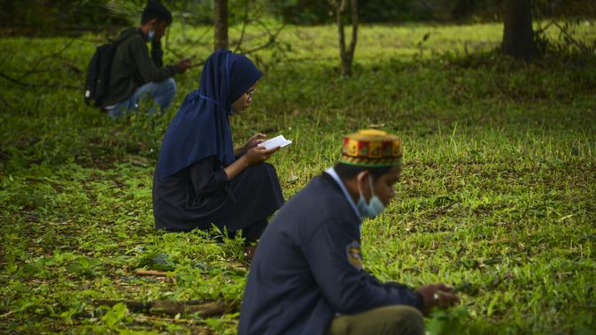 Orang-orang berdoa saat melakukan ziarah pada peringatan 16 tahun gempa bumi dan tsunami Aceh di sebuah kuburan massal di Siron, Sabtu (26/12/2020).  Peringatan di tengah pandemi COVID-19 itu tetap berlangsung secara sederhana melalui kegiatan ziarah kubur. (CHAIDEER MAHYUDDIN/AFP)