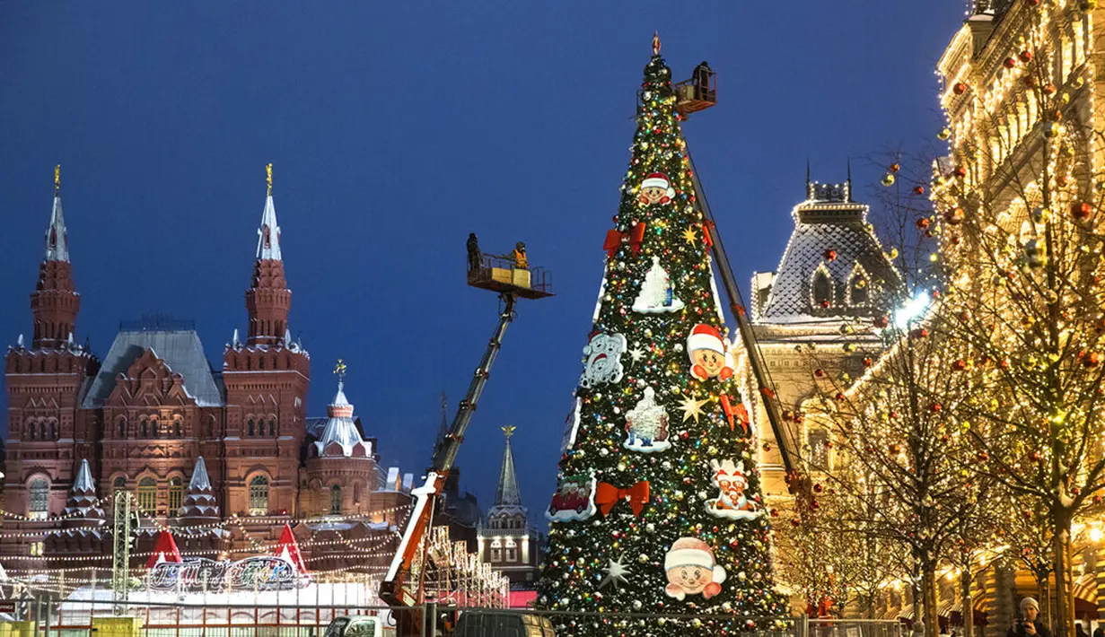 Petugas kota dengan crane mendirikan pohon Natal di Lapangan Merah, dengan Museum Sejarah, kiri, dan GUM State Department Store (kanan) di latar belakang, Moskow, Rusia, Senin (23/11/2020). Total kasus COVID-19 di Rusia saat ini telah mencapai lebih dari 2,1 juta. (AP Photo/Pavel Golovkin)